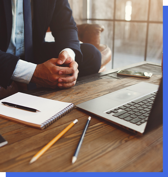 A business owner in front of a laptop with a notepad and pencils.