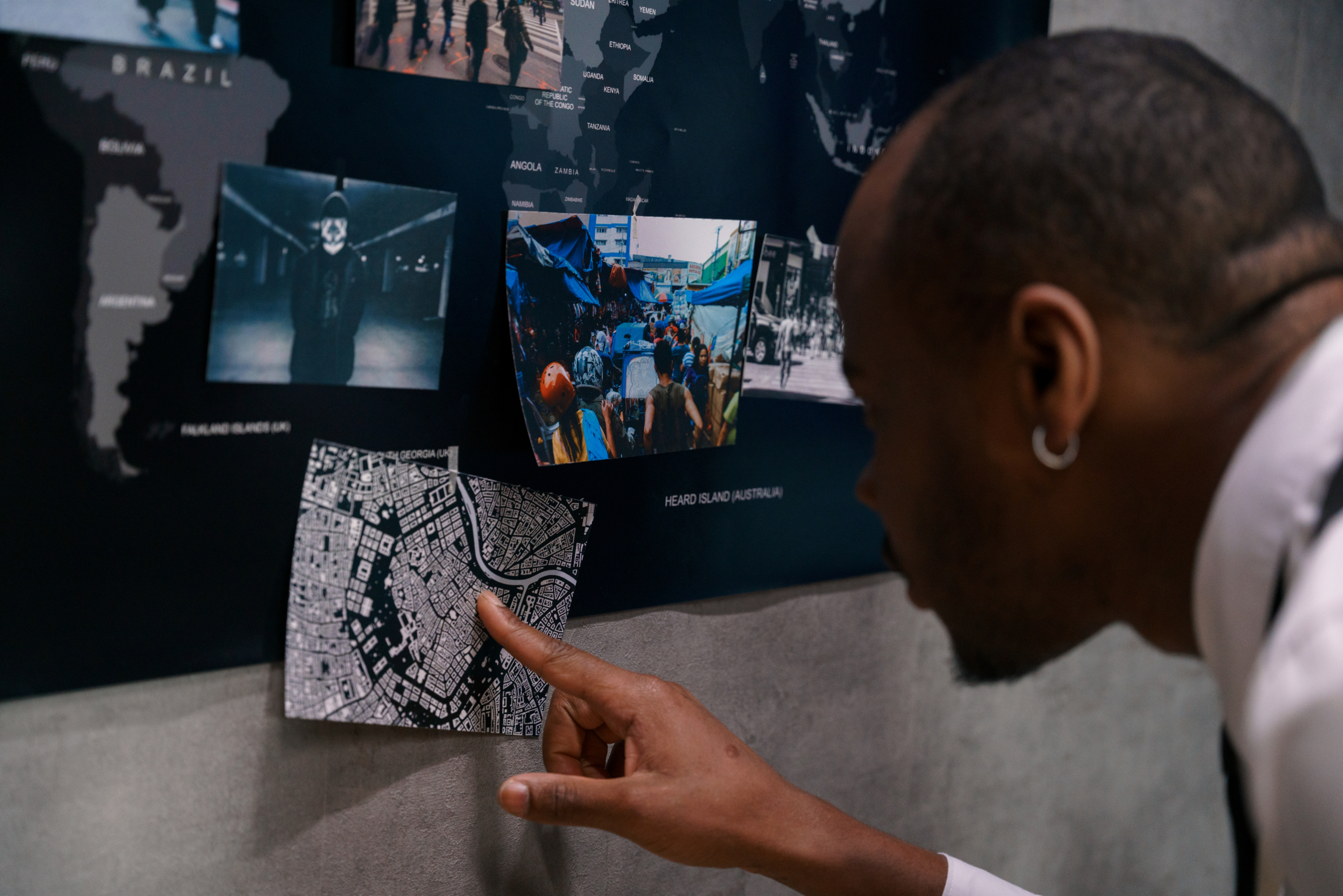 A portrait of a policeman leaning over a blackboard and looking at a map of the city, pointing at one of the houses